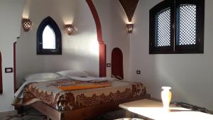 a bedroom with a bed with a table and two windows at Leyla Eco Resort Queen Suites in Luxor