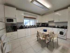 a kitchen with a table and chairs and a kitchen with white cabinets at Nazare apartamento em frente ao mar in Nazaré
