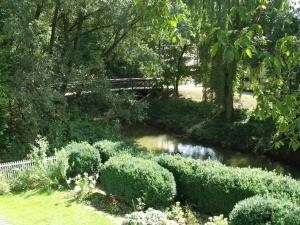 einen Garten mit einem Teich, einer Brücke und Büschen in der Unterkunft Haus am Bach - gemütliche Frühstückspension in Allershausen