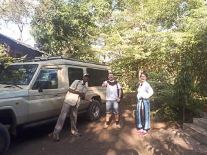 Un groupe de trois personnes debout à côté d'une camionnette dans l'établissement Shamba Hostel, à Usa River