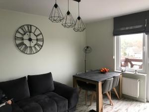 a living room with a couch and a clock on the wall at GOJA in Sztutowo