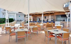 een restaurant met tafels en stoelen en een parasol bij Aparthotel Isla de Cabrera in Colonia Sant Jordi