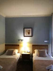 Eurobar & Hotel في أوكسفورد: غرفة فندقية بسريرين وطاولة بها مصباح