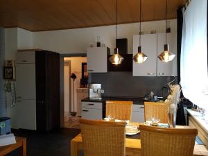 een keuken met een tafel met stoelen en verlichting bij Ferienwohnung Talblume in Marl
