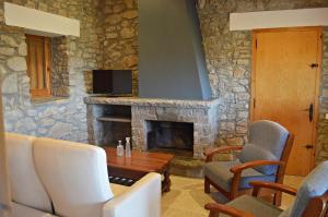 a living room with a stone fireplace and white chairs at Masoveria la Roca in Sagás