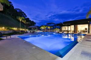 a large swimming pool with blue water at night at Quality Hotel Blumenau in Blumenau +61 photos