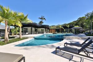 a swimming pool with two lounge chairs in front of a house at Quality Hotel Blumenau in Blumenau