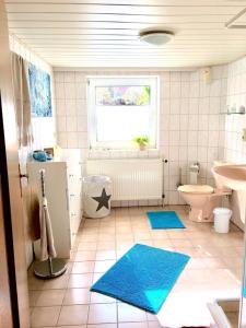 uma casa de banho com WC e um lavatório com tapetes azuis em Romantikgarten em Amelinghausen