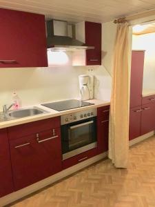 uma cozinha com armários vermelhos, um fogão e um lavatório em Romantikgarten em Amelinghausen