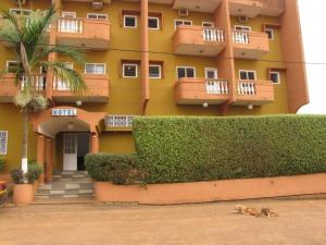 a dog laying on the ground in front of a building at Hotel Le Fibi in Yaoundé