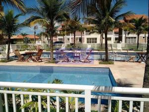 マンガラチバにあるApartamento Paraíso no Condado - Mangaratibaのヤシの木が植えられたプール(椅子、テーブル付)