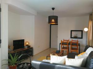 a living room with a couch and a table and a television at Apartamento playa de Levante in La Línea de la Concepción