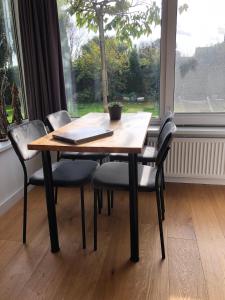 een houten tafel met vier stoelen en een raam bij B&B De nieuwendijk in Zuid-Beijerland