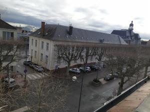 um grande edifício branco com um parque de estacionamento com carros em Bel appartement en plein coeur de ville em Le Creusot