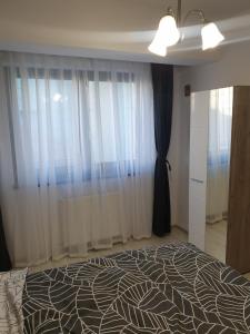 een slaapkamer met een bed en een raam met gordijnen bij Topaz Central Apartment in Bacău