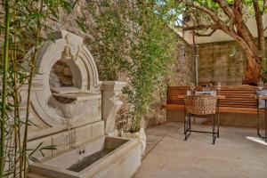 an outdoor seating area with a stone fountain and a bench at Heritage Hotel 19 in Split