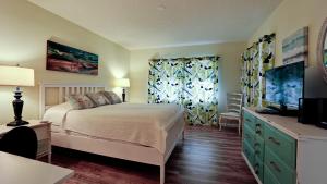 a bedroom with a bed and a dresser with a television at Shorewalk Vacation Villa in Bradenton +21 photos