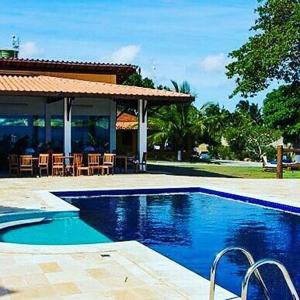 a swimming pool in front of a house with chairs at Pousada Villa das Palmeiras in Paripueira