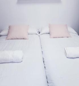 2 camas individuales con sábanas y almohadas blancas en Millan Astray en Ceuta