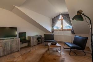 a living room with two chairs and a flat screen tv at Hotel ZUM STERNENHOF in Kössen