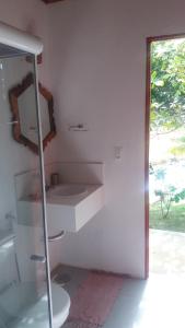a white bathroom with a sink and a window at Sitio Ilha do Meio in Itacimirim