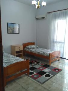 ein Schlafzimmer mit 2 Betten und einem Teppich auf dem Boden in der Unterkunft Vila Sula Guesthouse in Durrës