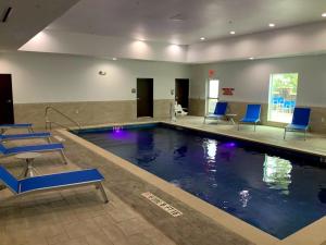 a swimming pool with blue chairs in a building at Comfort Suites Cedar Park - Austin Northwest in Cedar Park