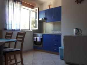 a kitchen with blue cabinets and a table and a window at Apartments Bambi in Lun