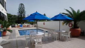 two tables and chairs with blue umbrellas next to a pool at Edificio Bahia Fragata Apartamento Loft 806 in San Andrés