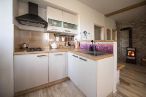 a kitchen with white cabinets and a fireplace at Apartmány HÁJOVNA Lipno in Loučovice