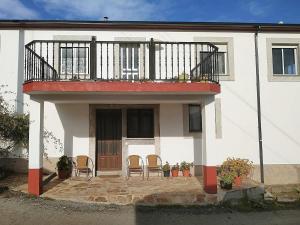 a white house with chairs and a balcony at Pension Casa Maruja in Castromayor