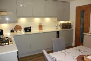 a kitchen with white cabinets and a table and a table and a table at Ground Floor Apartment in Montrose