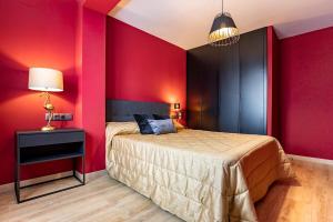 1 dormitorio con paredes rojas, 1 cama y 1 lámpara en Apartamento Superior Bali en Málaga