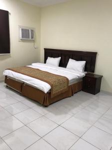 a bedroom with a large bed with a wooden headboard at Etlalet Al-Sharm Apartments in Yanbu