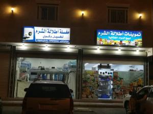un coche aparcado delante de una tienda por la noche en Etlalet Al-Sharm Apartments, en Yanbu