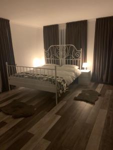 une chambre avec un lit blanc et un parquet dans l'établissement Casa De Sub Munte, à Buşteni