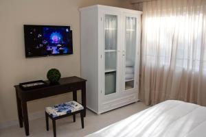 a bedroom with a white cabinet with a tv in it at Faro Norte Suites in Asunción