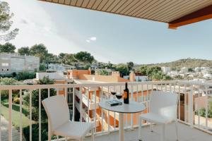 uma varanda com cadeiras brancas e uma mesa com uma garrafa de vinho em Hesperia Ciudad de Mallorca em Palma de Maiorca