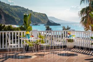 two tables and chairs on a balcony overlooking the ocean at Eneide in Palmi