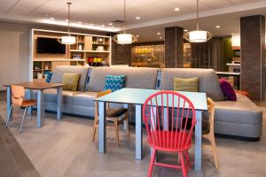 a living room with a couch and tables and chairs at Home2 Suites By Hilton Columbus/West, OH in Columbus