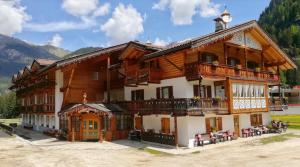 un gran edificio de madera con balcón y mesas en B&B Agriturismo Cèsa Ciasates, en Canazei