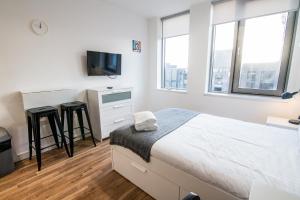 a white bedroom with a bed and a tv at Seel Street Studios in Liverpool