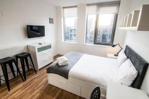 a bedroom with a bed and a tv and two windows at Seel Street Studios in Liverpool