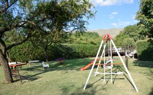 un parque infantil con columpio en un patio en Cabañas Babin Kuk en Merlo