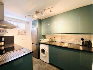 a kitchen with green cabinets and a washing machine at Toreblanca Lux in Fuengirola