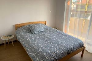 1 dormitorio con 1 cama con edredón azul y ventana en Carminho beach house en Vila do Conde