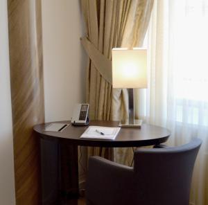 einem kleinen Tisch mit einer Lampe und einem Telefon darauf in der Unterkunft Hotel Vier Jahreszeiten Berlin City in Berlin