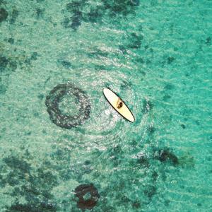 una tabla de surf flotando en el agua junto a una roca en The Moso, en Port Vila