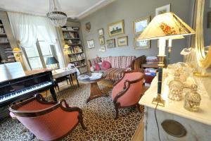 uma sala de estar com um piano e um sofá em La Maison D'hôtes du Parc em Ronchamp