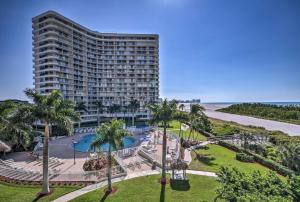 Un gran edificio con palmeras delante. en Sunny Getaway Community Amenities, Walk to Beach!, en Marco Island